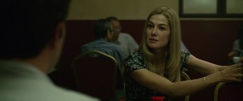 Movie still from “Gone Girl” (2014), directed by David Fincher – A woman sitting at a table in front of two other people; Close Up shot, Over the shoulder angle