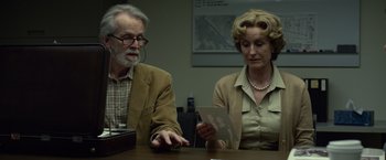 Movie still from “Gone Girl” (2014), directed by David Fincher – An older man and woman sitting at a table looking at a piece of paper; Medium shot, High angle