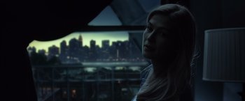 Movie still from “Gone Girl” (2014), directed by David Fincher – A woman looking out of a window at a city skyline at night; Close Up shot, Over the shoulder angle