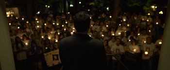 Movie still from “Gone Girl” (2014), directed by David Fincher – A crowd of people are gathered around a man in a suit; Extreme Wide shot, High angle