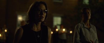 Movie still from “Gone Girl” (2014), directed by David Fincher – A woman wearing glasses standing in front of candles; Close Up shot, Over the shoulder angle