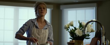 Movie still from “Gone Girl” (2014), directed by David Fincher – A woman standing in front of a counter holding a pan; Medium shot, Low angle