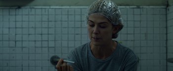 Movie still from “Gone Girl” (2014), directed by David Fincher – A woman with a hair net on her head is writing on a paper; Close Up shot, Over the shoulder angle