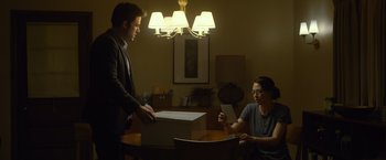 Movie still from “Gone Girl” (2014), directed by David Fincher – A man and a woman sitting at a dining room table; Medium shot, Low angle