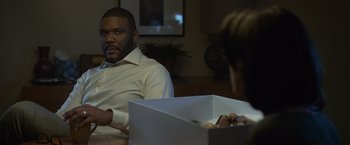 Movie still from “Gone Girl” (2014), directed by David Fincher – A man sitting at a table with a box in front of him; Medium shot, Over the shoulder angle