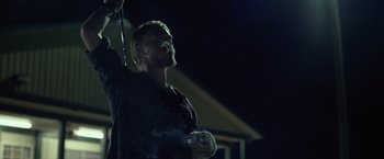 Movie still from “Gone Girl” (2014), directed by David Fincher – A man standing in the dark holding a cup; Medium shot, Low angle