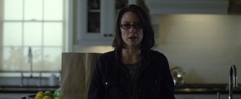 Movie still from “Gone Girl” (2014), directed by David Fincher – A woman wearing glasses sitting in a chair; Close Up shot, Over the shoulder angle