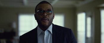 Movie still from “Gone Girl” (2014), directed by David Fincher – A person wearing glasses and a suit; Close Up shot, Low angle