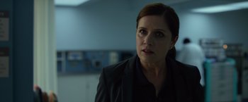 Movie still from “Gone Girl” (2014), directed by David Fincher – A woman in a black jacket is standing in a room; Close Up shot, Over the shoulder angle