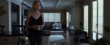 Movie still from “Gone Girl” (2014), directed by David Fincher – A woman holding a coffee mug in a living room; Medium shot, Low angle