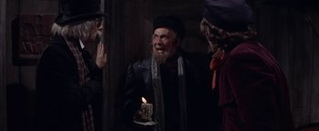 Movie still from “The Fearless Vampire Killers” (1967), directed by Roman Polanski – An old man holding a lit candle in front of two other people; Medium shot, Over the shoulder angle