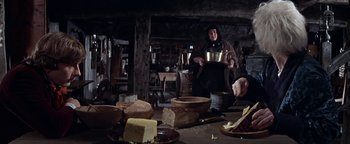 Movie still from “The Fearless Vampire Killers” (1967), directed by Roman Polanski – A man holding a bowl in front of a table full of food; Medium shot, Low angle