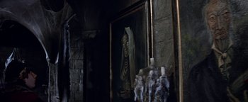 Movie still from “The Fearless Vampire Killers” (1967), directed by Roman Polanski – A painting of a man in a suit hanging on a wall next to candles; Medium shot, Low angle