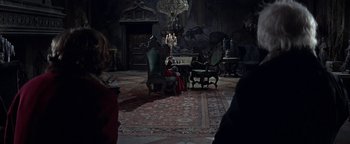 Movie still from “The Fearless Vampire Killers” (1967), directed by Roman Polanski – A living room filled with furniture next to a fire place; Wide shot, Over the shoulder angle