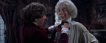 Movie still from “The Fearless Vampire Killers” (1967), directed by Roman Polanski – A man putting a tie on a man's head; Medium shot, Low angle