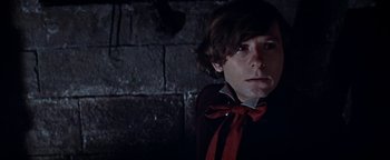 Movie still from “The Fearless Vampire Killers” (1967), directed by Roman Polanski – A young man wearing a red bow tie in front of a brick wall; Close Up shot, Low angle