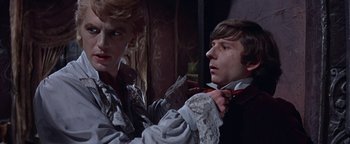 Movie still from “The Fearless Vampire Killers” (1967), directed by Roman Polanski – A man fixing another man's neck tie in front of a mirror; Medium shot, Over the shoulder angle