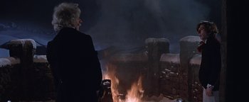 Movie still from “The Fearless Vampire Killers” (1967), directed by Roman Polanski – A person standing in front of a fire pit at night; Wide shot, Over the shoulder angle