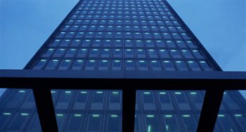 Movie still from “The Fifth Cord” (1971), directed by Luigi Bazzoni – A tall building with many windows lit up at night; Extreme Wide shot, Low angle