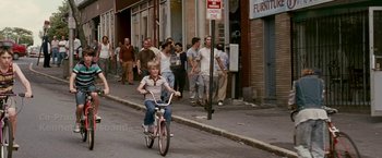 Movie still from “The Fighter” (2010), directed by David O. Russell – A young boy riding a bike down a street; Wide shot, High angle