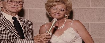 Movie still from “The Fighter” (2010), directed by David O. Russell – An older woman holding a microphone in her hand; Close Up shot, Low angle