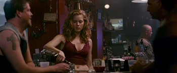 Movie still from “The Fighter” (2010), directed by David O. Russell – A woman in a red top is pouring a drink; Medium shot, Over the shoulder angle