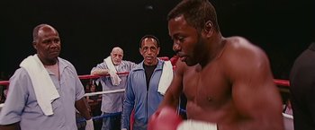 Movie still from “The Fighter” (2010), directed by David O. Russell – Two men in a boxing ring with a referee watching them; Medium shot, Over the shoulder angle