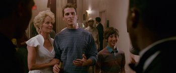 Movie still from “The Fighter” (2010), directed by David O. Russell – A group of people standing in a room; Medium shot, Over the shoulder angle