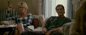 Movie still from “The Fighter” (2010), directed by David O. Russell – A man and a woman sitting on a couch in front of a window; Medium shot, Low angle