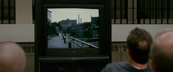 Movie still from “The Fighter” (2010), directed by David O. Russell – A large television screen with a picture of a bridge; Wide shot, Over the shoulder angle