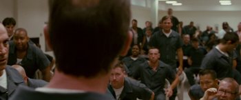 Movie still from “The Fighter” (2010), directed by David O. Russell – A group of men sitting in front of each other in a room; Medium shot, Over the shoulder angle