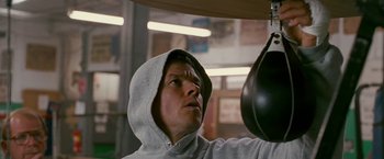 Movie still from “The Fighter” (2010), directed by David O. Russell – A man in a hooded sweatshirt is practicing boxing; Close Up shot, Low angle