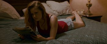 Movie still from “The Fighter” (2010), directed by David O. Russell – A woman laying on a bed looking at a book; Medium shot, High angle