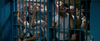 Movie still from “The Fighter” (2010), directed by David O. Russell – A group of men standing next to each other in a jail cell; Medium shot, High angle