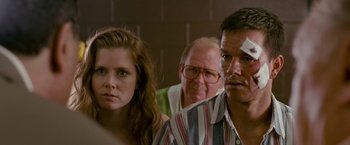 Movie still from “The Fighter” (2010), directed by David O. Russell – A man and a woman standing next to each other in front of another man; Close Up shot, Over the shoulder angle