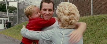 Movie still from “The Fighter” (2010), directed by David O. Russell – A man and a woman hug a boy in front of a fence; Medium shot, Over the shoulder angle