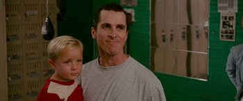 Movie still from “The Fighter” (2010), directed by David O. Russell – A man standing next to a young boy in front of a green wall; Close Up shot, Low angle
