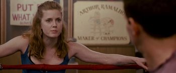 Movie still from “The Fighter” (2010), directed by David O. Russell – A woman sitting in a boxing ring in front of a sign; Close Up shot, Over the shoulder angle