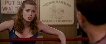 Movie still from “The Fighter” (2010), directed by David O. Russell – A woman standing in a boxing ring in front of a sign; Medium shot, Over the shoulder angle