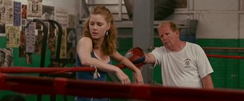 Movie still from “The Fighter” (2010), directed by David O. Russell – A woman in a boxing ring getting ready to punch a man; Medium shot, Over the shoulder angle