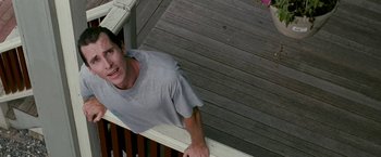 Movie still from “The Fighter” (2010), directed by David O. Russell – A man standing on top of a wooden railing next to a porch; Medium shot, High angle