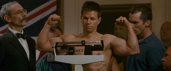 Movie still from “The Fighter” (2010), directed by David O. Russell – A man standing in front of a weight scale; Medium shot, Low angle