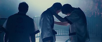 Movie still from “The Fighter” (2010), directed by David O. Russell – A man is tying a belt around his waist; Medium shot, Low angle