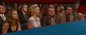Movie still from “The Fighter” (2010), directed by David O. Russell – A woman and a man sitting in front of an audience; Medium shot, High angle