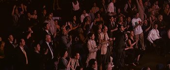 Movie still from “The Fighter” (2010), directed by David O. Russell – A group of people sitting in a stadium with their hands raised; Wide shot, High angle