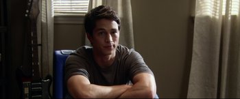 Movie still from “The Final Destination” (2009), directed by David R. Ellis – A young man sitting on a couch with his arms crossed; Medium shot, Over the shoulder angle