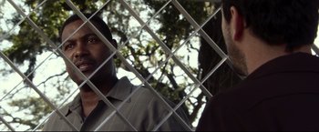 Movie still from “The Final Destination” (2009), directed by David R. Ellis – A man looking through a fence at a tree in the background; Close Up shot, Over the shoulder angle