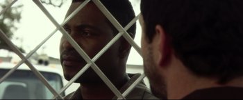 Movie still from “The Final Destination” (2009), directed by David R. Ellis – Two men are looking at each other through a fence; Close Up shot, Over the shoulder angle