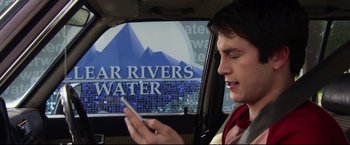 Movie still from “The Final Destination” (2009), directed by David R. Ellis – A man in the back of a car looking at his cell phone; Close Up shot, Over the shoulder angle