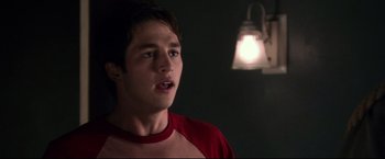 Movie still from “The Final Destination” (2009), directed by David R. Ellis – A young man in a red shirt is standing in front of a lamp; Close Up shot, Over the shoulder angle